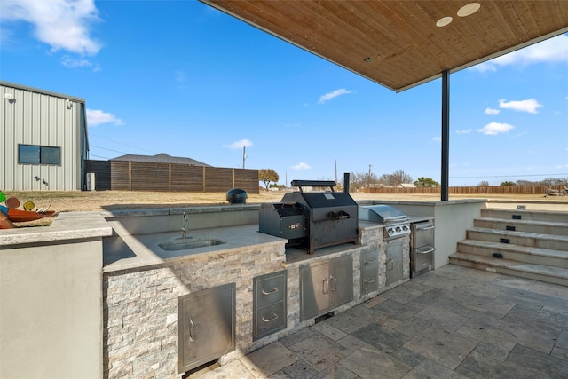 view of patio with a sink, exterior kitchen, grilling area, and fence