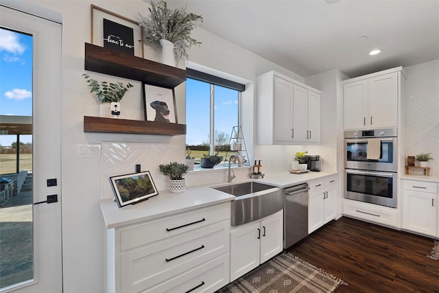 kitchen with decorative backsplash, dark wood-style flooring, stainless steel appliances, light countertops, and a sink