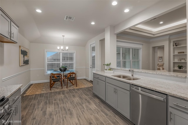 kitchen with light stone countertops, pendant lighting, stainless steel appliances, and a sink