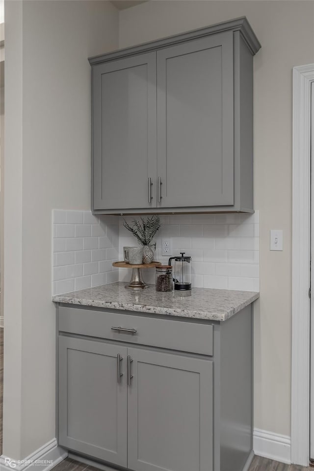 bar featuring baseboards, decorative backsplash, and wood finished floors