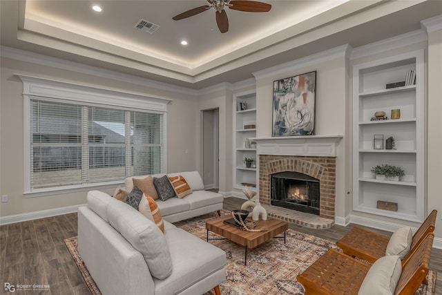 living room with visible vents, built in features, baseboards, dark wood-style floors, and a raised ceiling