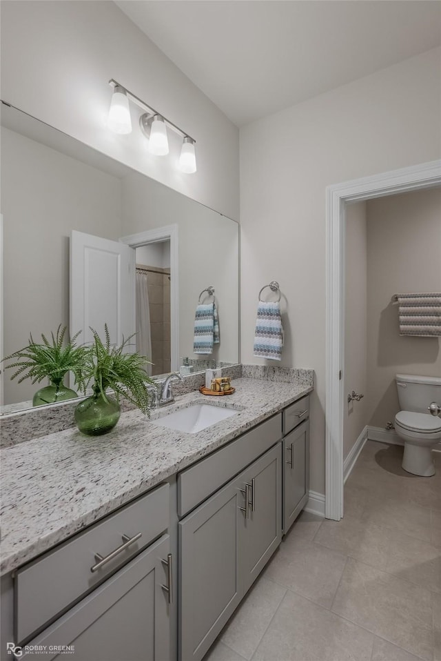 bathroom featuring baseboards, vanity, toilet, and tile patterned floors