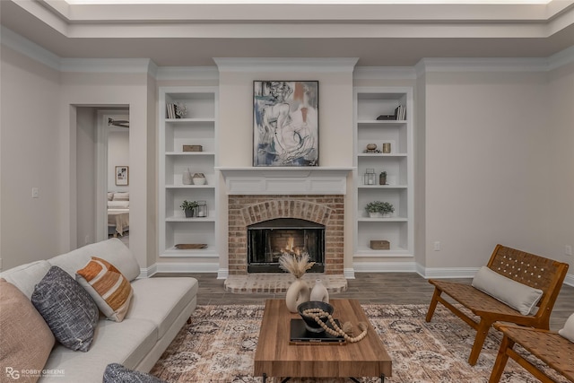 living area with built in features, crown molding, a fireplace, and wood finished floors