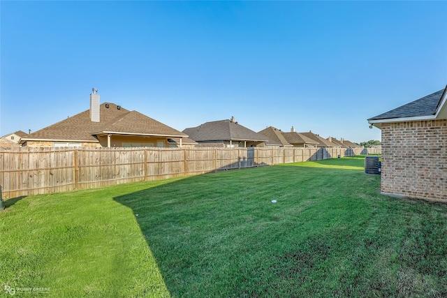 view of yard with central AC, a fenced backyard, and a residential view