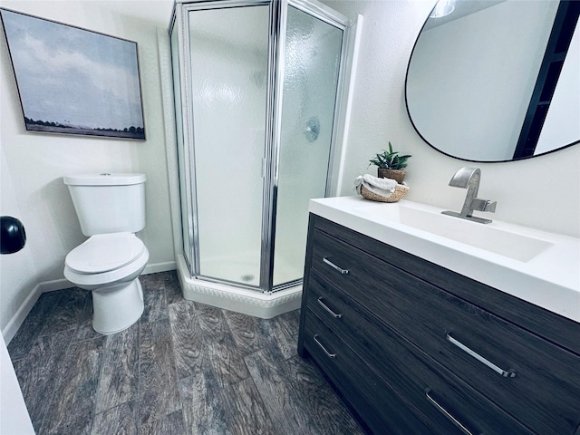 full bath featuring baseboards, toilet, wood finished floors, vanity, and a shower stall