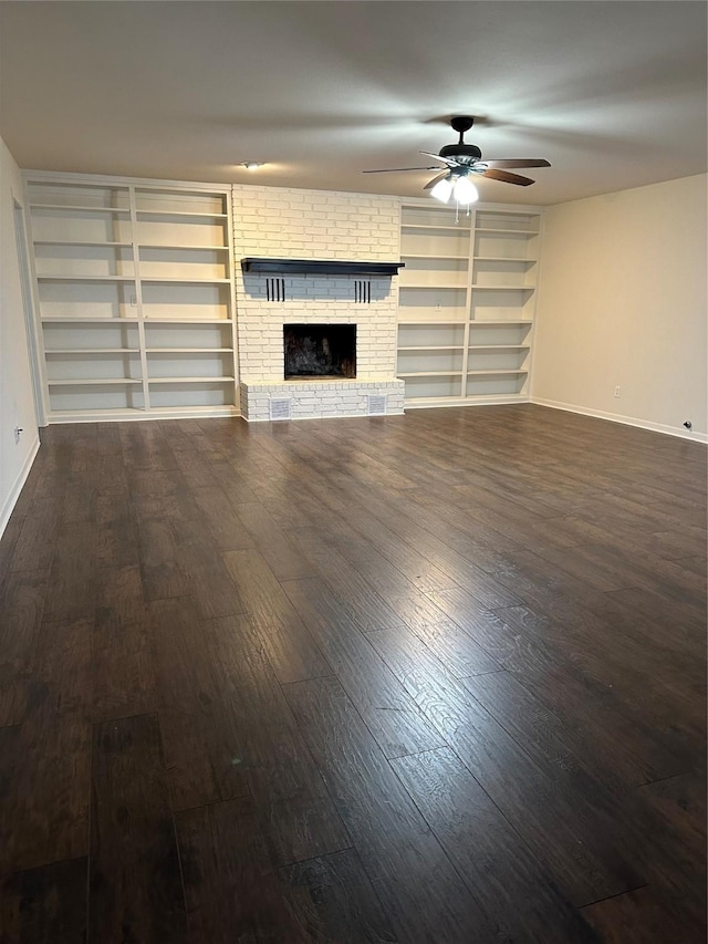 unfurnished living room featuring a brick fireplace, baseboards, dark wood finished floors, and a ceiling fan