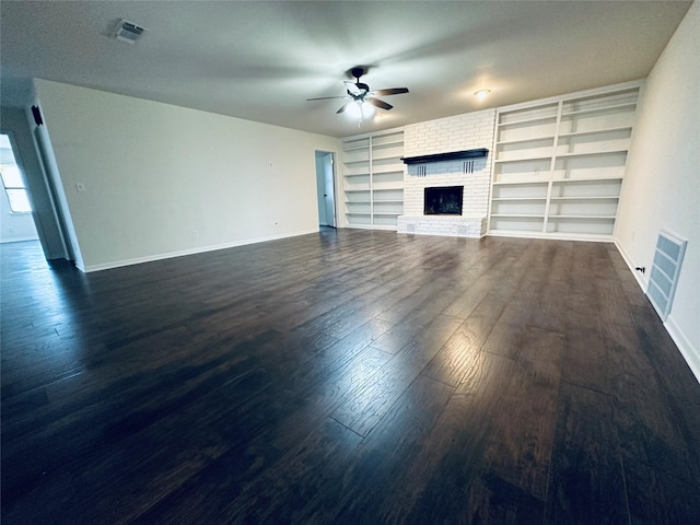 unfurnished living room featuring a brick fireplace, ceiling fan, visible vents, and dark wood finished floors