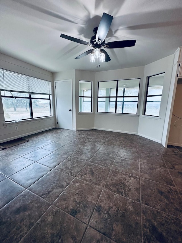 spare room featuring ceiling fan and baseboards
