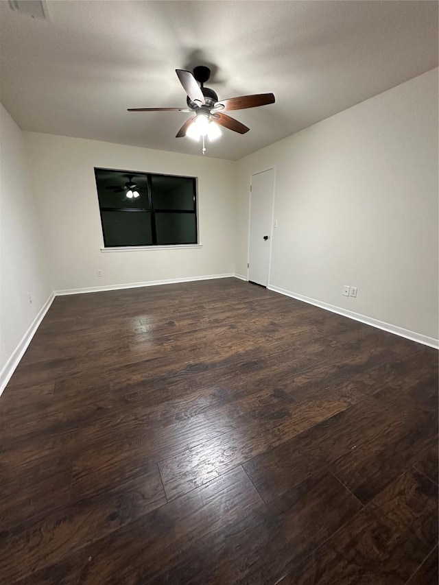 spare room with a ceiling fan, dark wood finished floors, and baseboards