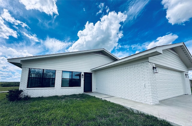 ranch-style home with a garage, a front lawn, concrete driveway, and brick siding