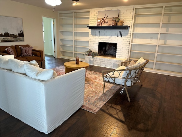 living area with a brick fireplace, built in shelves, and wood finished floors
