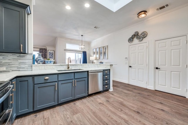 kitchen featuring visible vents, appliances with stainless steel finishes, a sink, light wood-type flooring, and a peninsula