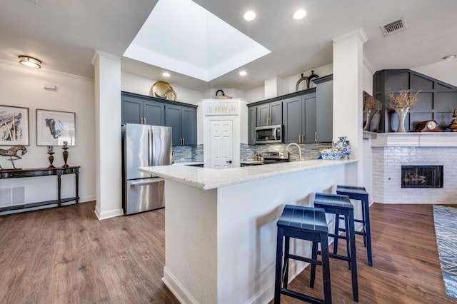 kitchen with a peninsula, appliances with stainless steel finishes, dark wood-style flooring, and visible vents