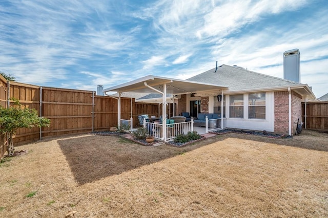 back of house with brick siding, a yard, a chimney, a patio, and a fenced backyard