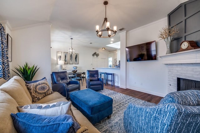 living room featuring wood finished floors, visible vents, baseboards, ornamental molding, and a brick fireplace