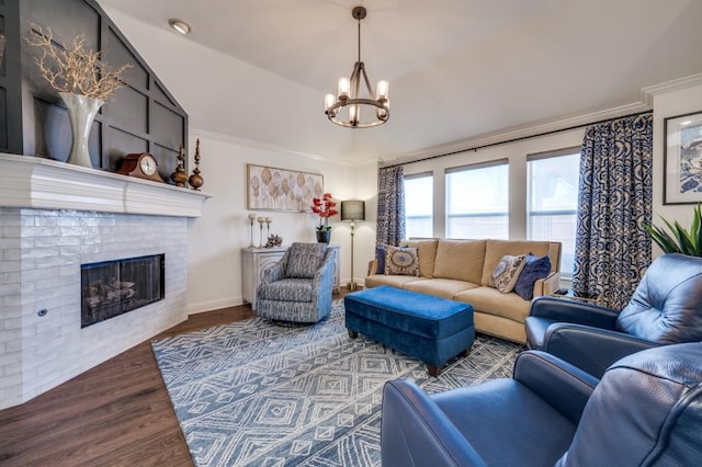 living area featuring a notable chandelier, a fireplace, wood finished floors, baseboards, and ornamental molding