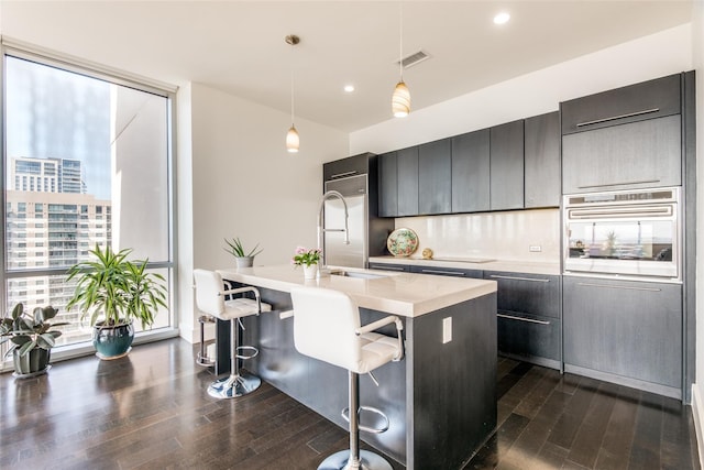 kitchen featuring a breakfast bar area, oven, visible vents, a view of city, and decorative light fixtures