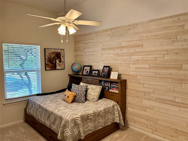 bedroom with wooden walls, ceiling fan, baseboards, and carpet