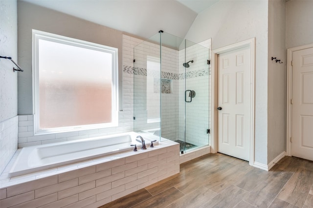 bathroom featuring a shower stall, a garden tub, wood finished floors, and vaulted ceiling