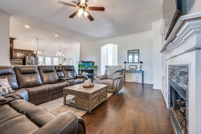 living room featuring ornamental molding, recessed lighting, ceiling fan with notable chandelier, a fireplace, and dark wood-style flooring