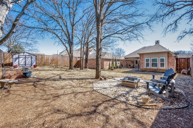 view of yard with a fire pit, a fenced backyard, and an outdoor structure