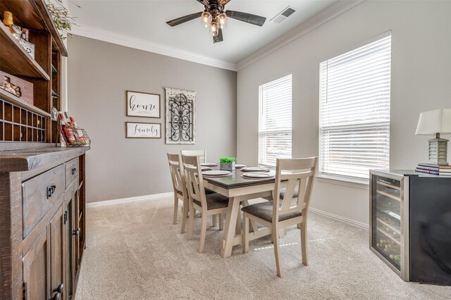 dining room with visible vents, wine cooler, crown molding, baseboards, and light colored carpet