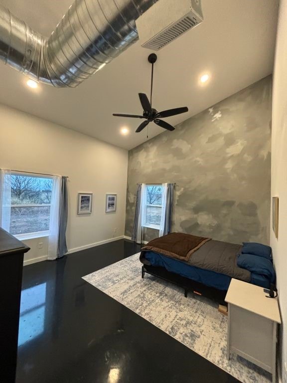 bedroom with lofted ceiling, ceiling fan, concrete floors, visible vents, and baseboards