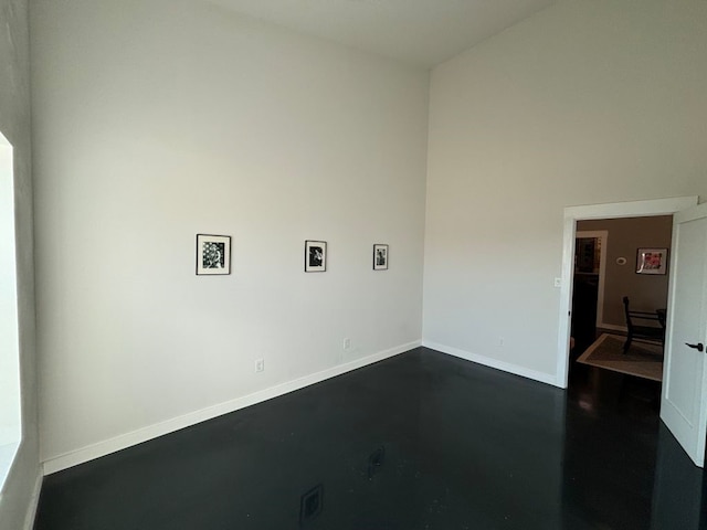 unfurnished room with baseboards and concrete flooring