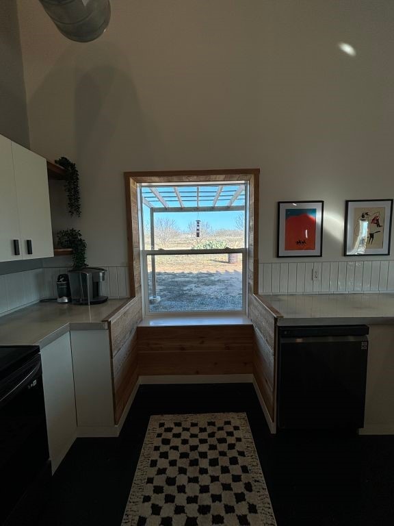 kitchen with light countertops, fridge, black electric range, and white cabinetry