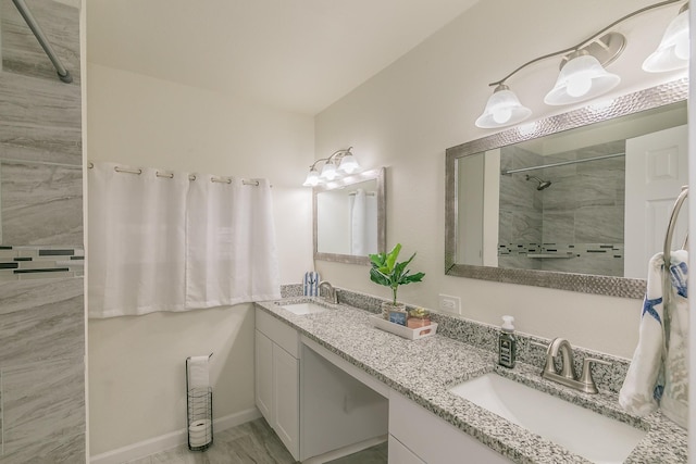 bathroom with double vanity, baseboards, a sink, and tiled shower