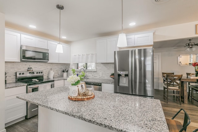 kitchen featuring appliances with stainless steel finishes, decorative light fixtures, and white cabinetry