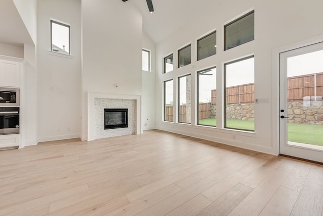 3206 Bexar St, Rockwall, TX 75032 - unfurnished living room featuring high vaulted ceiling, light wood finished floors, a glass covered fireplace, and ceiling fan