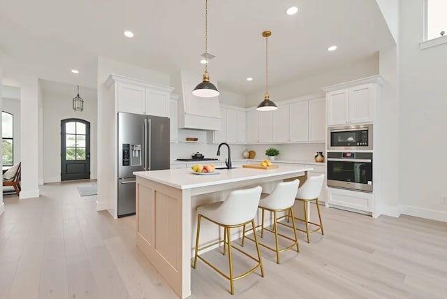 3206 Bexar St, Rockwall, TX 75032 - kitchen with stainless steel appliances, light wood-style floors, recessed lighting, a kitchen island with sink, and light countertops