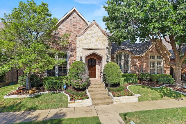 view of front of property featuring stone siding, brick siding, and a front lawn