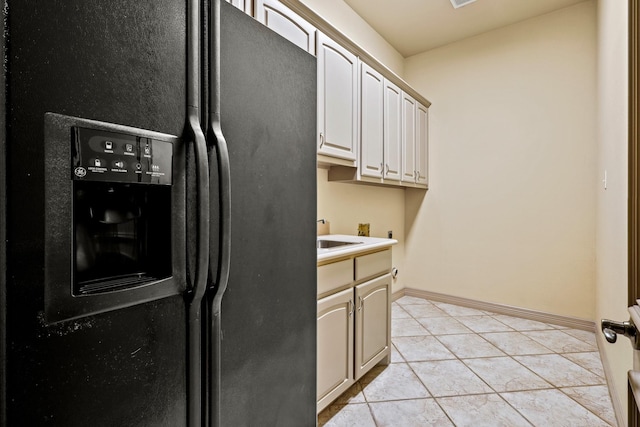 kitchen with baseboards, light tile patterned flooring, light countertops, and black fridge with ice dispenser