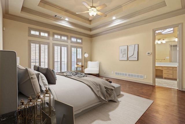 bedroom with dark wood-type flooring, a raised ceiling, visible vents, and crown molding