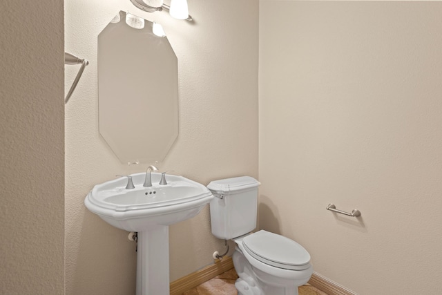 bathroom featuring baseboards, a sink, and toilet