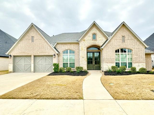 french country style house featuring concrete driveway, brick siding, an attached garage, and french doors