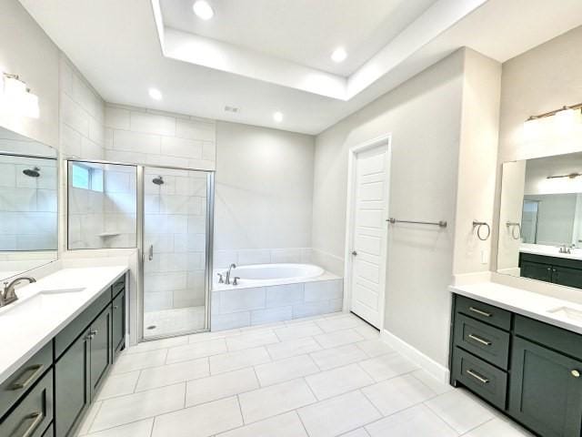 full bath featuring two vanities, a sink, a bath, and a shower stall