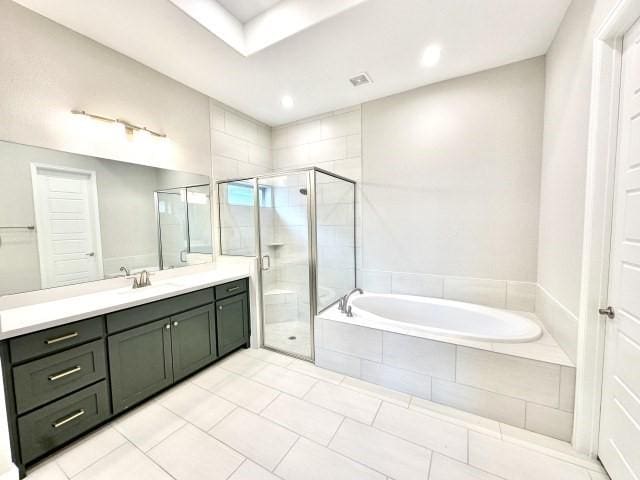 bathroom featuring a stall shower, visible vents, a garden tub, and vanity