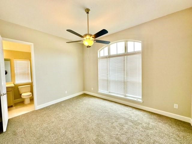 unfurnished bedroom featuring a ceiling fan, carpet flooring, connected bathroom, and baseboards