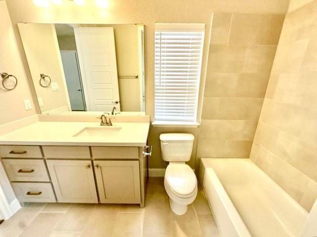 bathroom with a tub to relax in, baseboards, toilet, tile patterned flooring, and vanity