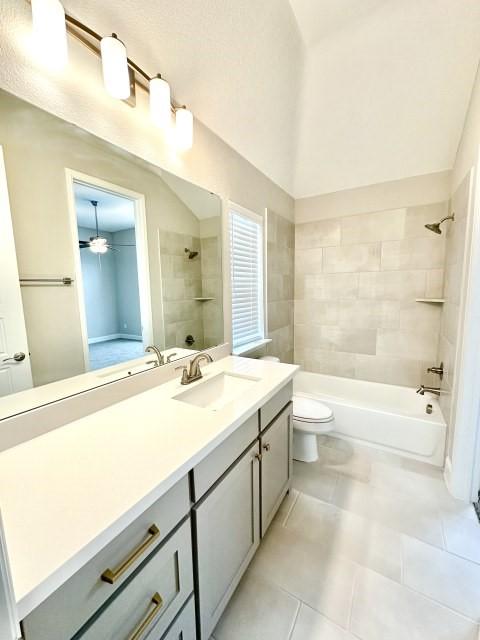 bathroom with a ceiling fan, toilet, tile patterned flooring, tub / shower combination, and vanity