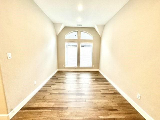 spare room featuring visible vents, baseboards, and wood finished floors