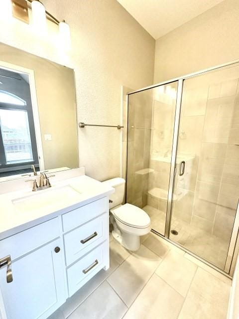 full bath featuring toilet, a shower stall, vanity, and tile patterned floors