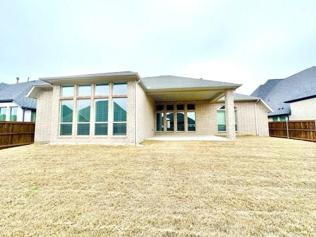 rear view of property with a yard, fence, a patio, and brick siding