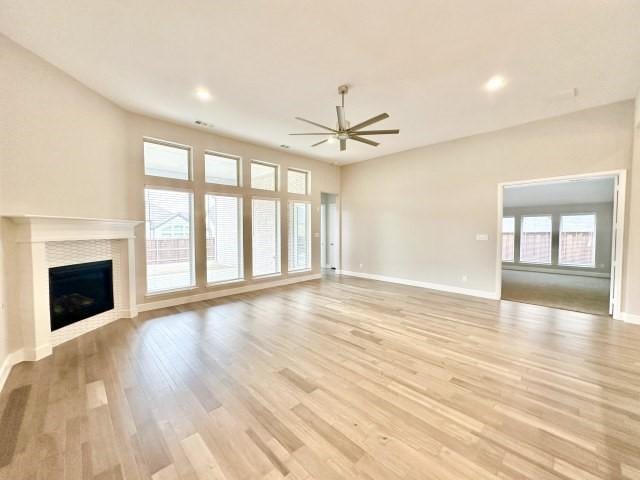 unfurnished living room featuring light wood finished floors, baseboards, ceiling fan, a fireplace, and recessed lighting