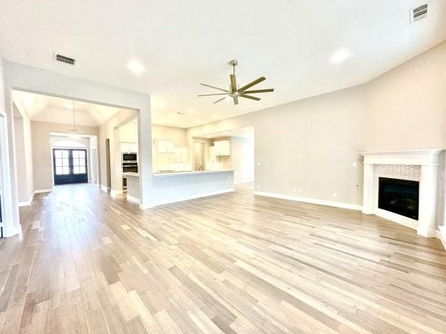 unfurnished living room featuring light wood-style floors, a fireplace, and visible vents