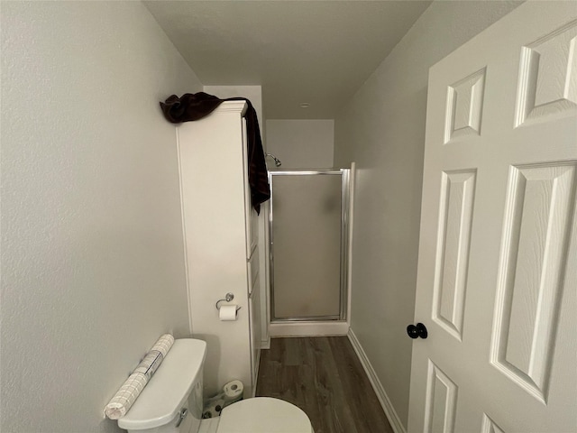 full bathroom with a stall shower, wood finished floors, toilet, and baseboards