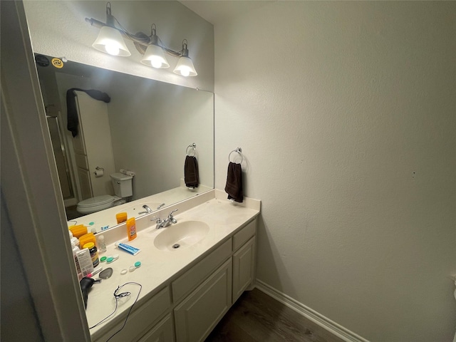 bathroom with baseboards, vanity, toilet, and wood finished floors